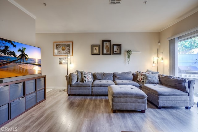 living room with crown molding, visible vents, baseboards, and wood finished floors