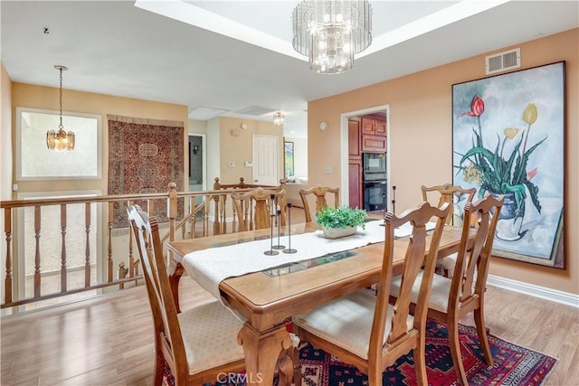 dining area featuring visible vents, wood finished floors, baseboards, and a chandelier