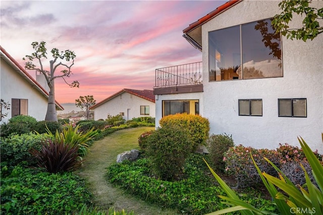 property exterior at dusk with stucco siding and a balcony