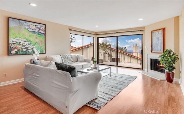 living room with a lit fireplace, recessed lighting, baseboards, and wood finished floors