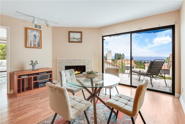 dining space featuring baseboards, visible vents, light wood-type flooring, and a tile fireplace