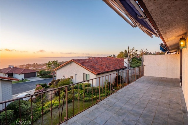 patio terrace at dusk featuring a balcony