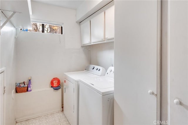 laundry area with cabinet space, separate washer and dryer, and baseboards