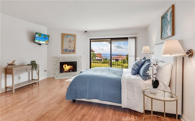 bedroom with a fireplace, access to outside, wood finished floors, and baseboards