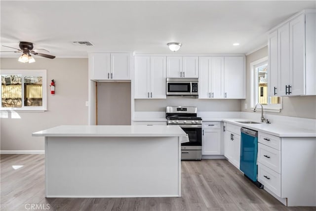 kitchen featuring a ceiling fan, a sink, a kitchen island, stainless steel appliances, and white cabinets