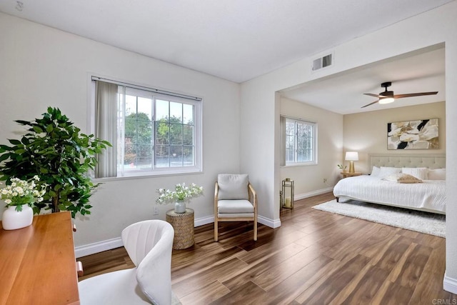 bedroom featuring ceiling fan, visible vents, baseboards, and wood finished floors