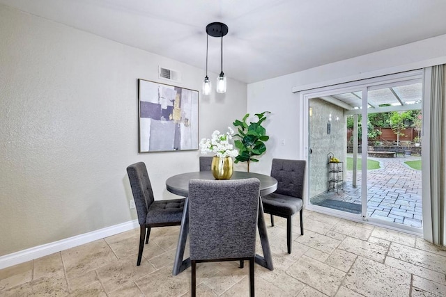 dining room with stone tile floors, visible vents, and baseboards