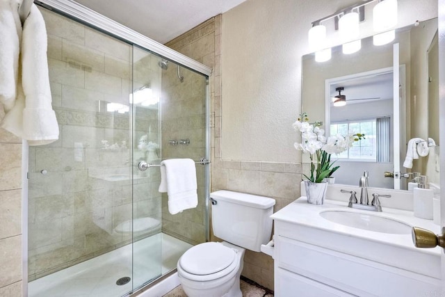 full bathroom with vanity, tile walls, toilet, and a shower stall