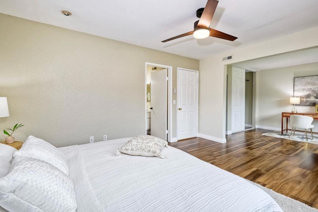 bedroom with a ceiling fan, wood finished floors, visible vents, and baseboards