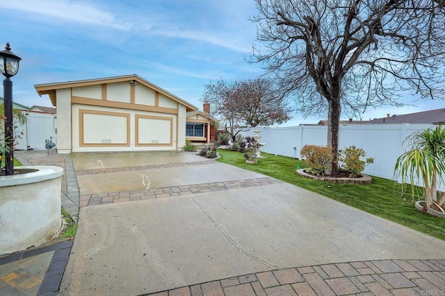 view of front facade with stucco siding, a front lawn, and fence