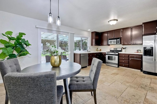 kitchen featuring dark brown cabinets, light countertops, stone tile flooring, stainless steel appliances, and a sink