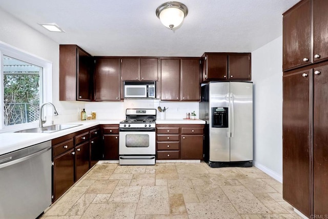 kitchen featuring light countertops, stone tile floors, appliances with stainless steel finishes, and a sink