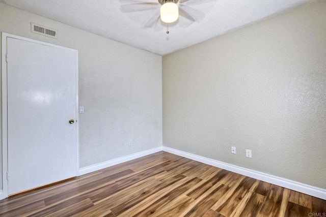 unfurnished room with visible vents, baseboards, wood finished floors, and a ceiling fan