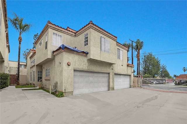 exterior space with stucco siding, driveway, fence, an attached garage, and a tiled roof