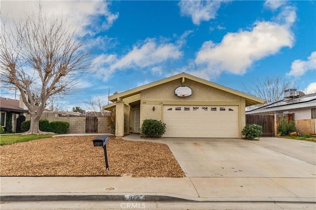 single story home featuring concrete driveway, an attached garage, fence, and stucco siding