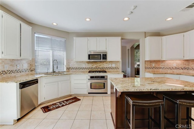 kitchen featuring visible vents, a sink, arched walkways, appliances with stainless steel finishes, and light tile patterned floors