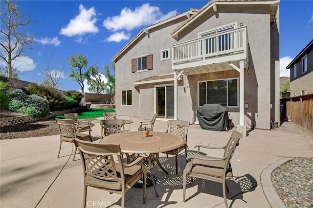 rear view of house featuring stucco siding, a patio, a fenced backyard, outdoor dining area, and a balcony