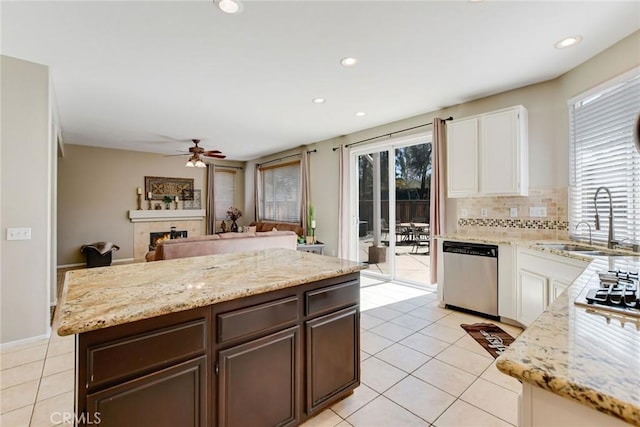 kitchen featuring a sink, plenty of natural light, stainless steel dishwasher, dark brown cabinetry, and decorative backsplash