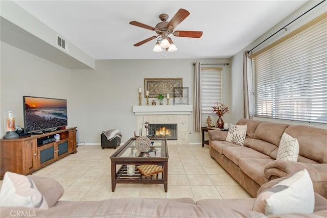 living area featuring light tile patterned floors, visible vents, a tiled fireplace, and ceiling fan