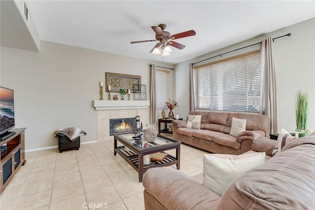 living room with a ceiling fan, visible vents, baseboards, light tile patterned flooring, and a tiled fireplace