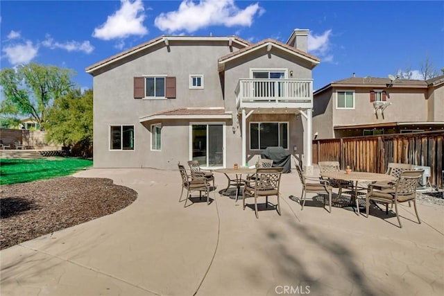 back of house with outdoor dining space, stucco siding, a balcony, and fence