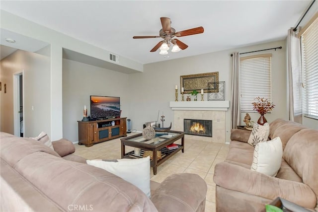 living area with a tiled fireplace, light tile patterned floors, visible vents, and ceiling fan