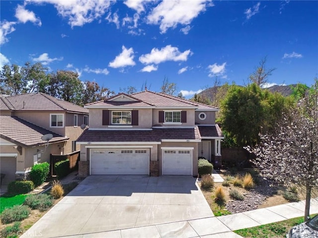 traditional home featuring a tile roof, an attached garage, concrete driveway, and stucco siding