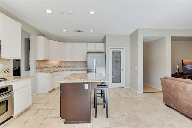 kitchen featuring stainless steel appliances, visible vents, a center island, and white cabinetry