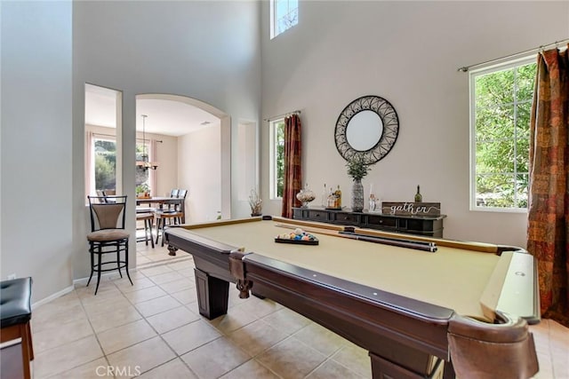 rec room with arched walkways, light tile patterned floors, a healthy amount of sunlight, and pool table