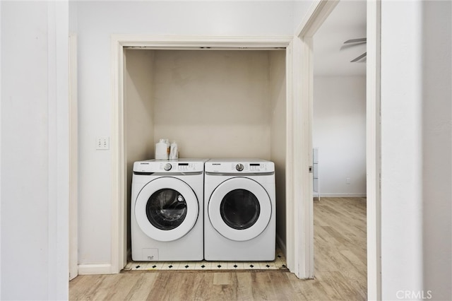 washroom featuring washer and dryer, baseboards, and wood finished floors