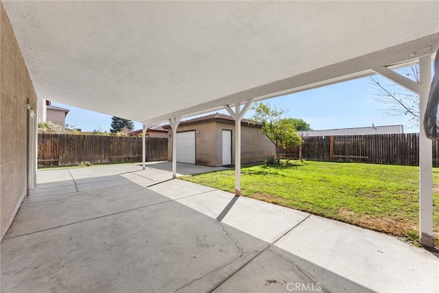 view of patio / terrace featuring an outbuilding, a fenced backyard, and a carport