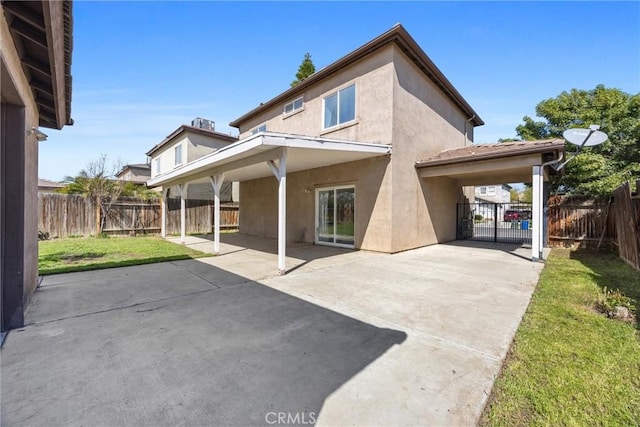 back of house with a patio area, a lawn, a fenced backyard, and stucco siding