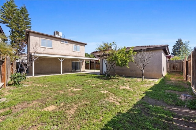 rear view of property featuring a patio area, stucco siding, a yard, and a fenced backyard