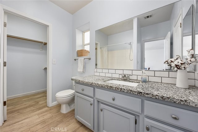 full bath featuring a spacious closet, visible vents, toilet, a shower with shower curtain, and wood finished floors