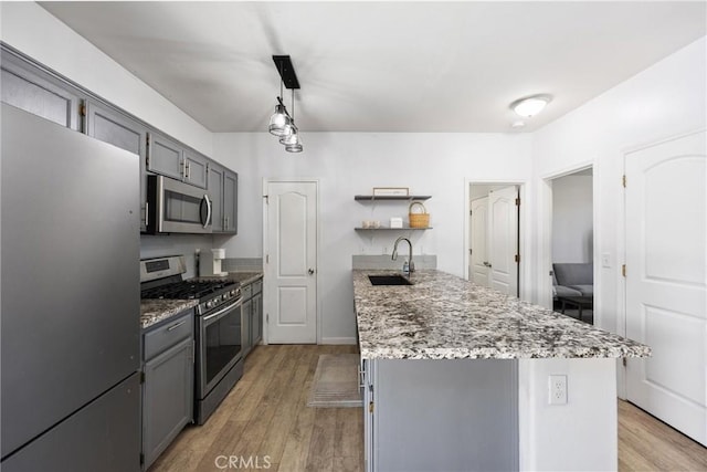 kitchen featuring appliances with stainless steel finishes, open shelves, gray cabinetry, and a sink