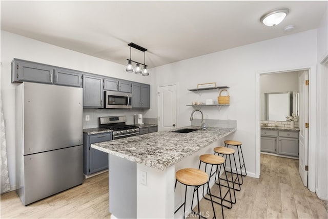 kitchen with open shelves, a peninsula, a sink, appliances with stainless steel finishes, and a kitchen bar