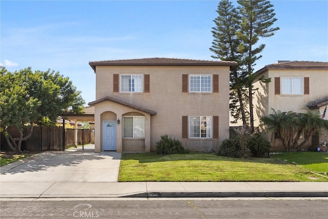 traditional-style home featuring an attached carport, fence, a front yard, stucco siding, and driveway