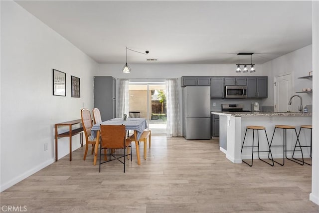 dining area featuring visible vents, baseboards, light wood-style floors, and a notable chandelier