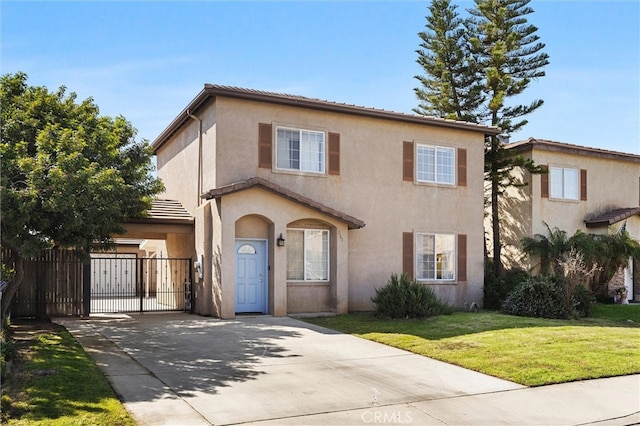 view of front of property featuring a front lawn, fence, concrete driveway, stucco siding, and a gate