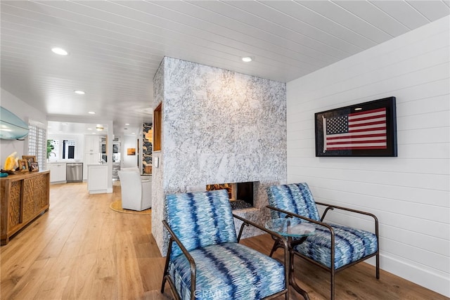 living area featuring light wood finished floors, wooden walls, a multi sided fireplace, recessed lighting, and wooden ceiling