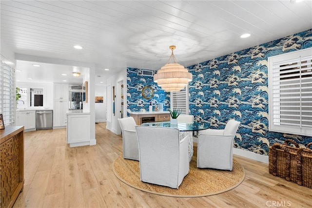 dining area with light wood finished floors, wallpapered walls, and baseboards