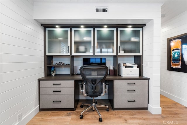 office space with visible vents, wooden walls, light wood-style flooring, and built in study area