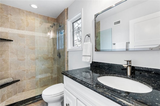 full bathroom with vanity, a shower stall, toilet, and visible vents