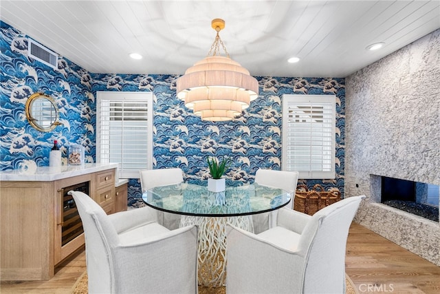 dining space featuring recessed lighting, wine cooler, light wood-style floors, a fireplace, and wallpapered walls