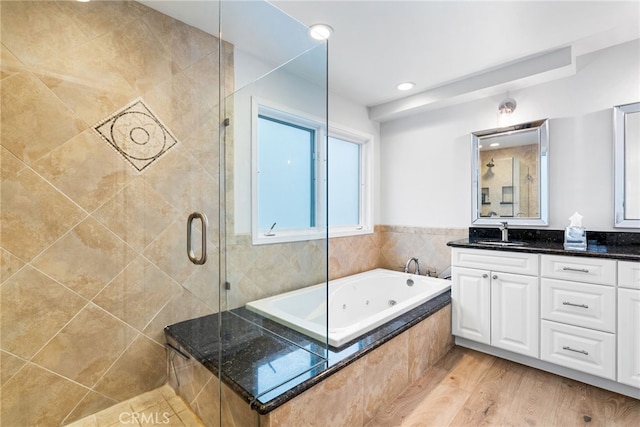 bathroom with vanity, a jetted tub, wood finished floors, and a stall shower