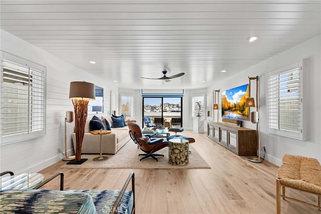 living area with baseboards, a healthy amount of sunlight, a ceiling fan, and light wood-style floors