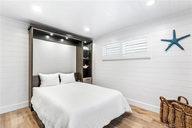 bedroom with recessed lighting, wood finished floors, and wood walls