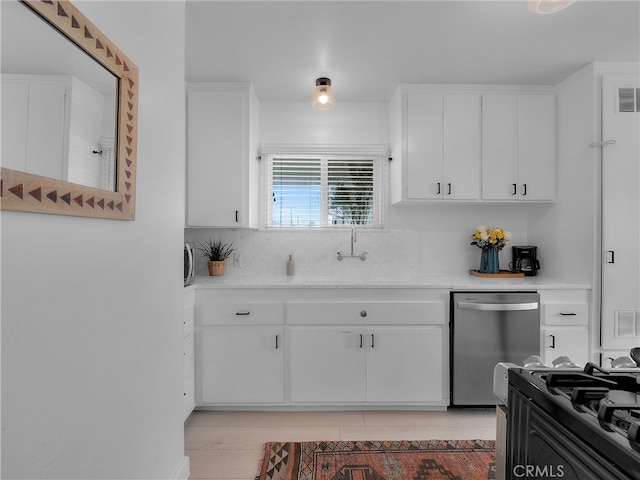 kitchen with black range with gas stovetop, white cabinetry, light countertops, and stainless steel dishwasher