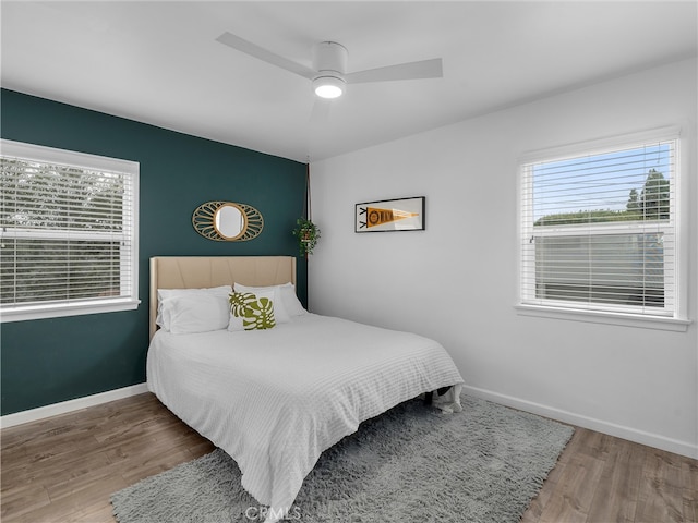 bedroom featuring wood finished floors, baseboards, and ceiling fan