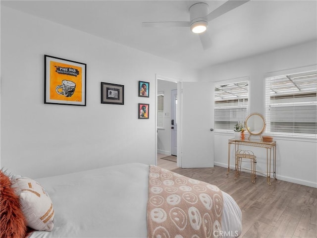 bedroom featuring baseboards, wood finished floors, and a ceiling fan